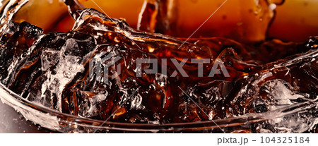 Splashing of Cola and Ice. Cola soda and ice splashing fizzing or floating up to top of surface. Close up of ice in cola water. Texture of carbonate drink with bubbles in glass. Cold drink background 104325184
