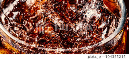 Splashing of Cola and Ice. Cola soda and ice splashing fizzing or floating up to top of surface. Close up of ice in cola water. Texture of carbonate drink with bubbles in glass. Cold drink background 104325215