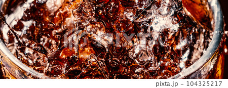 Splashing of Cola and Ice. Cola soda and ice splashing fizzing or floating up to top of surface. Close up of ice in cola water. Texture of carbonate drink with bubbles in glass. Cold drink background Splashing of Cola and Ice. Cola soda and ice splashing fizzing or floating up to top of surface. Close up of ice in cola water. Texture of carbonate drink with bubbles in glass. Cold drink background 104325217