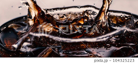 Splashing of Cola and Ice. Cola soda and ice splashing fizzing or floating up to top of surface. Close up of ice in cola water. Texture of carbonate drink with bubbles in glass. Cold drink background Splashing of Cola and Ice. Cola soda and ice splashing fizzing or floating up to top of surface. Close up of ice in cola water. Texture of carbonate drink with bubbles in glass. Cold drink background 104325223