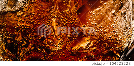 Splashing of Cola and Ice. Cola soda and ice splashing fizzing or floating up to top of surface. Close up of ice in cola water. Texture of carbonate drink with bubbles in glass. Cold drink background Splashing of Cola and Ice. Cola soda and ice splashing fizzing or floating up to top of surface. Close up of ice in cola water. Texture of carbonate drink with bubbles in glass. Cold drink background 104325228