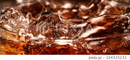 Splashing of Cola and Ice. Cola soda and ice splashing fizzing or floating up to top of surface. Close up of ice in cola water. Texture of carbonate drink with bubbles in glass. Cold drink background Splashing of Cola and Ice. Cola soda and ice splashing fizzing or floating up to top of surface. Close up of ice in cola water. Texture of carbonate drink with bubbles in glass. Cold drink background 104325232