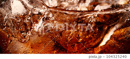 Splashing of Cola and Ice. Cola soda and ice splashing fizzing or floating up to top of surface. Close up of ice in cola water. Texture of carbonate drink with bubbles in glass. Cold drink background Splashing of Cola and Ice. Cola soda and ice splashing fizzing or floating up to top of surface. Close up of ice in cola water. Texture of carbonate drink with bubbles in glass. Cold drink background 104325240