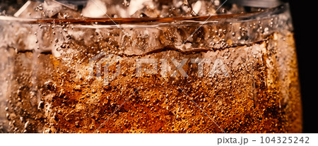 Splashing of Cola and Ice. Cola soda and ice splashing fizzing or floating up to top of surface. Close up of ice in cola water. Texture of carbonate drink with bubbles in glass. Cold drink background 104325242