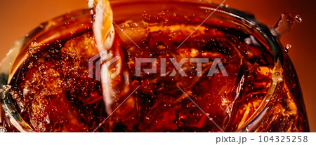 Splashing of Cola and Ice. Cola soda and ice splashing fizzing or floating up to top of surface. Close up of ice in cola water. Texture of carbonate drink with bubbles in glass. Cold drink background 104325258