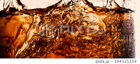 Splashing of Cola and Ice. Cola soda and ice splashing fizzing or floating up to top of surface. Close up of ice in cola water. Texture of carbonate drink with bubbles in glass. Cold drink background 104325259