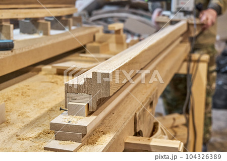 Carpenter milling wooden handrail with router manual milling machine in workshop close up. Handyman processes timber piece with electric instrument Carpenter milling wooden handrail with router manual milling machine in workshop close up. Handyman processes timber piece with electric instrument 104326389