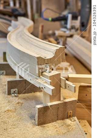 Bending wooden staircase handrail made of oak planks and plywood on table closeup. Detail of stairs fence in carpentry workshop Bending wooden staircase handrail made of oak planks and plywood on table closeup. Detail of stairs fence in carpentry workshop 104326391
