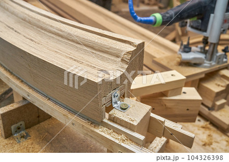 Bending wooden staircase handrail made of oak planks and plywood on table closeup. Detail of stairs fence in carpentry workshop 104326398