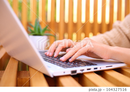 Closeup of unrecognizable woman typing on laptop keyboard while working outdoor, remote job. 104327516