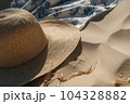 Wicker straw hat and blue white sarong pareo on beach sand. Summer sea vacation concept 104328882