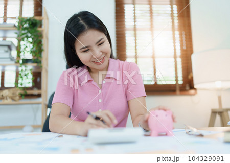 investment plan, young asian woman keep coin money in jar and using calculator to calculate savings. 104329091