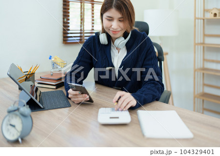 financial, Planning, Marketing and Accounting, portrait of Asian employee checking financial statements using and calculator, tablet computer and smart phone at work. 104329401
