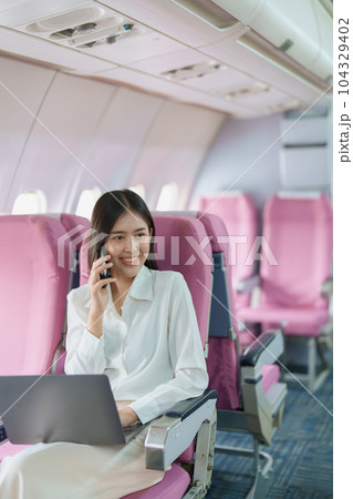 Asian business woman passenger sitting on business class luxury plane while working using smart phone mobile talking or video conference and travel concept. 104329402