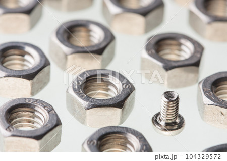 Metallic steel hex nuts and a small fastener bolt Metallic steel hex nuts and a small fastener bolt 104329572