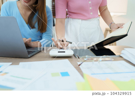 Financial analysts analyzing business reports on planned investment projects during corporate meeting discussions showcase successful teamwork with marketing plan, computers and calculators to work. Financial analysts analyzing business reports on planned investment projects during corporate meeting discussions showcase successful teamwork with marketing plan, computers and calculators to work. 104329915