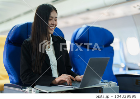 Asian business woman passenger sitting on business class plane while working on laptop computer with simulated space using on board wireless connection. Asian business woman passenger sitting on business class plane while working on laptop computer with simulated space using on board wireless connection. 104329999