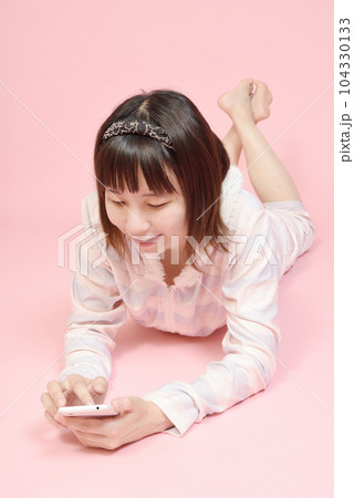 パジャマ姿でスマホを操作する女性 パジャマ姿でスマホを操作する女性 104330133