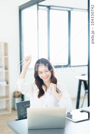 Portrait of a woman business owner showing a happy smiling face as he has successfully invested her business using computers and financial budget documents at work. Portrait of a woman business owner showing a happy smiling face as he has successfully invested her business using computers and financial budget documents at work. 104330742
