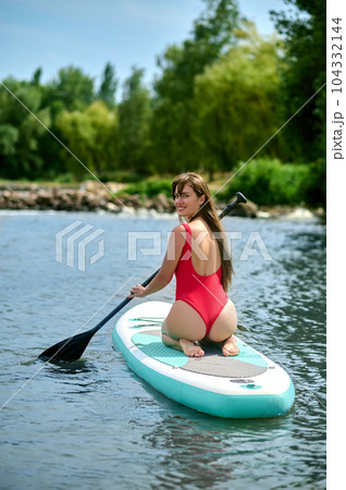 Woman relaxing on sup surfboard, floating on water, recreational sports, paddle boarding. Woman relaxing on sup surfboard, floating on water, recreational sports, paddle boarding. 104332144