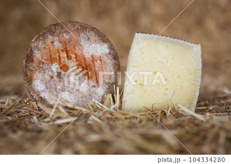 head and chunks of aged hard cheese in hayloft head and chunks of aged hard cheese in hayloft 104334280