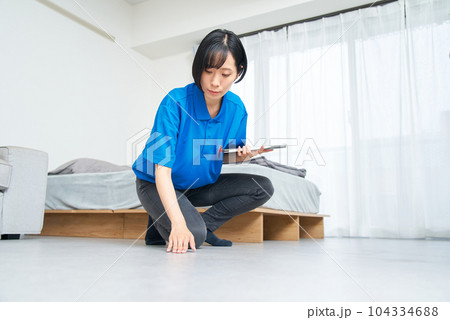部屋の状態を確認する作業着姿の女性の写真素材 [104334688] - PIXTA