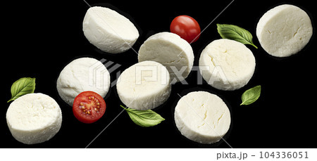 Falling mozzarella cheese slices on black background Falling mozzarella cheese slices on black background 104336051