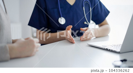 Doctor and patient talking to each other during current health examination while sitting at the desk in clinic, closeup of hand. Perfect medical service and medicine concept Doctor and patient talking to each other during current health examination while sitting at the desk in clinic, closeup of hand. Perfect medical service and medicine concept 104336262