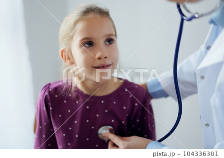 Happy smiling child girl patient at usual medical inspection. Doctor and kid patient at home. Medicine, healthcare concepts 104336301