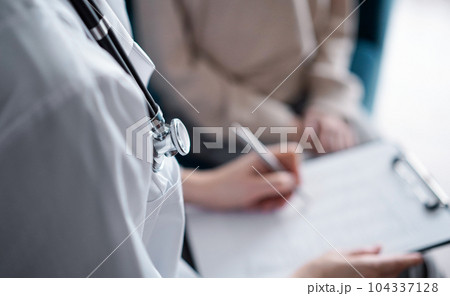 Doctor woman and kid boy patient at home medical exam, stethoscope close up. The pediatrician filling up medical form on clipboard, close up. Medicine, healthcare concepts 104337128