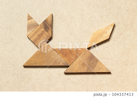 Wooden tangram in cat sitting or lying shape on wood background 104337413