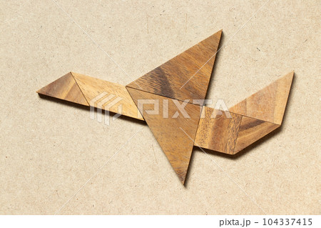 Wooden tangram in flying plane shape on wood background 104337415