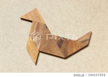 Wooden tangram in seal or sea lion shape on wood background Wooden tangram in seal or sea lion shape on wood background 104337459