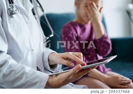 Doctor woman and kid patient at home. The pediatrician uses a tablet computer, close up. Medicine, healthcare concepts 104337488