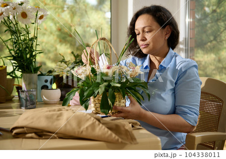 Multi-ethnic pregnant woman, inspired female florist making a flower arrangement in a floral shop. Small business. Creative hobby. Flower design studio and store concept. Multi-ethnic pregnant woman, inspired female florist making a flower arrangement in a floral shop. Small business. Creative hobby. Flower design studio and store concept. 104338011