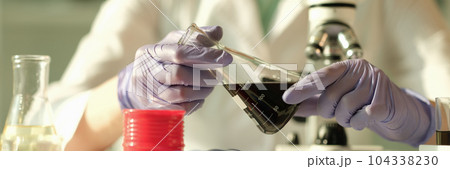 Scientist chemist holding in his hands flask with oil in chemical laboratory closeup 104338230
