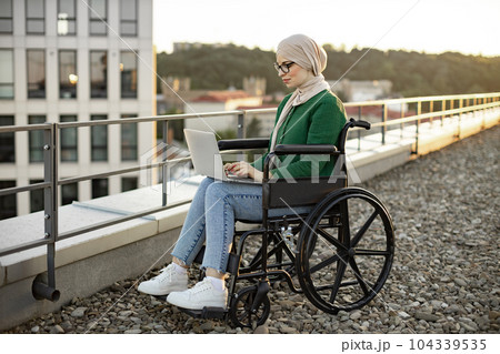 Female with mobility impairment using computer in open air Female with mobility impairment using computer in open air 104339535
