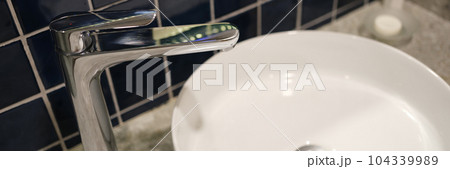 White sink and metal faucet in bathroom closeup 104339989