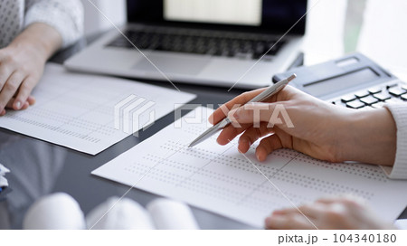 Woman accountant using a calculator and laptop computer while counting taxes for a client. Business audit concepts Woman accountant using a calculator and laptop computer while counting taxes for a client. Business audit concepts 104340180