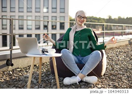 Muslim woman with gyan mudra smiling in bean bag on roof Muslim woman with gyan mudra smiling in bean bag on roof 104340313