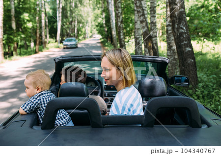 Mom, dad and little son in a convertible car. Summer family road trip to nature 104340767