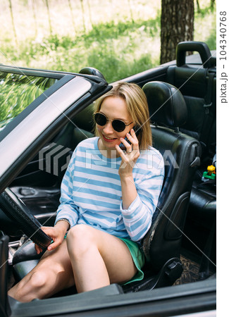 A woman is driving a convertible car. Summer road trip to nature 104340768