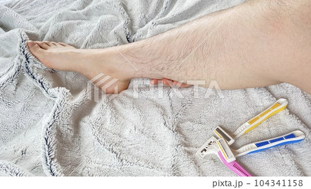 ピンクと黄色と青色の使い捨てカミソリとムダ毛の生えた女性の脛 ピンクと黄色と青色の使い捨てカミソリとムダ毛の生えた女性の脛 104341158