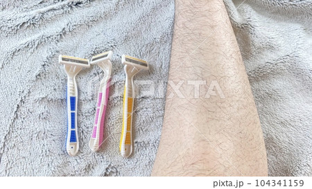 ピンクと黄色と青色の使い捨てカミソリとムダ毛の生えた女性の脛 ピンクと黄色と青色の使い捨てカミソリとムダ毛の生えた女性の脛 104341159