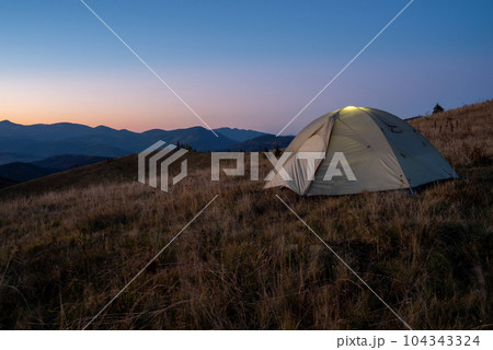 A tourist tent stands on top of a mountain. Camping at the top of the mountain. 104343324