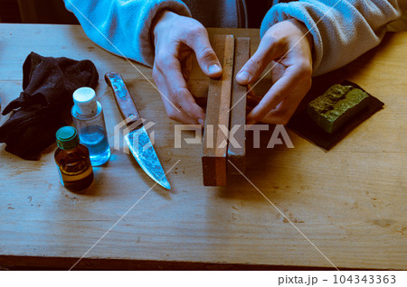 Different grinding stones in the hands. The master holds stones for sharpening in his hands. Rub the stone against the stone. Different grinding stones in the hands. The master holds stones for sharpening in his hands. Rub the stone against the stone. 104343363