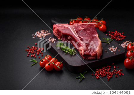 Raw juicy beef t-bone steak with salt, spices and herbs 104344001