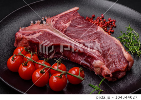 Raw juicy beef t-bone steak with salt, spices and herbs Raw juicy beef t-bone steak with salt, spices and herbs 104344027