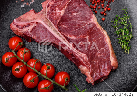 Raw juicy beef t-bone steak with salt, spices and herbs Raw juicy beef t-bone steak with salt, spices and herbs 104344028