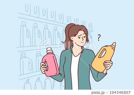 Woman holds bottles of laundry detergent or cleaning product standing near shelves in supermarket 104346807